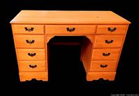Front view of wooden kneehole desk showing nine drawers and metal pulls