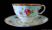 Side view of teacup on saucer showing floral pattern and gold trim