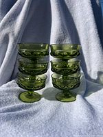 Front view of the stack of six green Indiana Glass goblets arranged in two groups of three each, showing the shape and color.