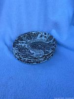 Stack of 5 small saucers showing Paisley pattern laid on blue fabric.