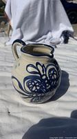 Side angled view of the vintage blue ceramic pitcher showing the handle and spout with floral designs.