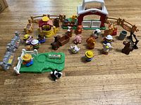 Overview of Fisher Price Little People farm toys including barn, animals, people, fences, and other accessories on wood surface