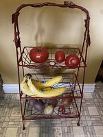 Front view showing the rack holding bananas, potatoes, onions, and artificial tomatoes.