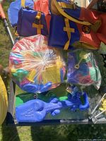 Two kids' life jackets hanging and assorted beach toys including molds and shovels placed on a surface.
