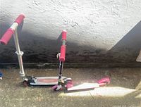 Pair of Razor scooters side by side with red handles, one black deck and one pink deck