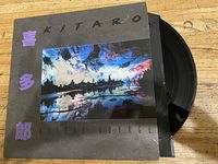 Vinyl record partially pulled out of its sleeve showing the album cover with predominantly black background and colorful image.