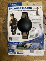 Photo of the front of the Fitter First Classic Balance Board packaging showing product name, brand and usage benefits.