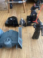Photo of Star Wars figures and accessories standing on floor including Darth Vader helmet, Captain Phasma figure, Darth Maul figure on stand, TIE Fighter toy