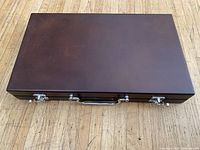 Closed dark brown wooden case of backgammon set showing metal clasps and handle