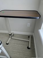 Side angle of the tray table showing the metal frame and wheels on carpeted floor