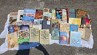 Photo showing assortment of books arranged on ground with titles visible including cookbooks and children's books