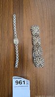 Top view of vintage silver floral bracelet and vintage Swiss made wristwatch on wooden surface.