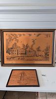 Photo showing both copper etched drawings, a larger and smaller framed piece on a white surface.