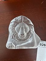 Front view of the translucent glass lion head figure showing detailed facial features and mane.