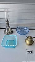 Photo of four items: vintage oil lamp, small jug, heart-shaped blue glass bowl, and square blue-green hobnail glass bowl on white surface.