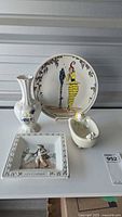 Photo showing all four porcelain items: decorative plate, floral vase, small dish with birds, and newsvendor plaque.