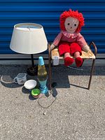 Photo of retro floral vinyl-top stool, vintage Raggedy Ann doll, untested blue lava lamp, and untested table lamp with white shade
