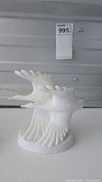 Front view of the white porcelain Royal Doulton bird figurine 'Going Home', showing detailed stylized birds and smooth glossy finish.