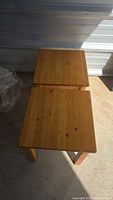 Top view of two small square pine tables showing wood grain and natural finish.