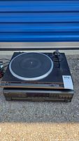 Technics turntable and receiver stacked outdoors on concrete with lot number tag visible.