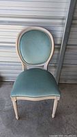 Front view of vintage French style dining chair with mint green upholstery showing oval back and padded seat.