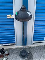 Full standing view of the black metal vintage standing lamp showing its conical shade and slender pole.