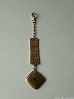 Full view of fob locket with clasp, chain, square panels, and diamond-shaped locket with sapphire