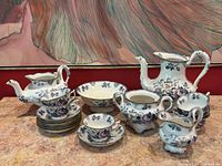 Full tea set arranged on a surface showing all major components: two teapots, sugar bowl, creamer, serving bowl, six cups and saucers set.