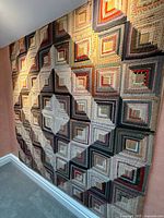Full view of quilt hanging on wall at angle.