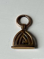 View of the front side of the gold filled watch fob pendant showing the openwork arch design and attachment ring.