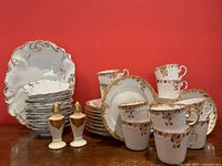 Full lot shown with all coffee cups, plates, serving bowls, and salt & pepper shakers in front of red background.