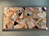 Front view of the vintage hand-stitched crazy quilt mounted on canvas, showing the patchwork of various textiles sewn in irregular patterns with visible signs of wear and fraying.