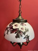 View of antique hanging light with hand painted floral glass shade, antique brass metal fixture, and electrified candles below.