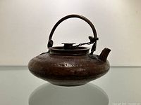 Right side profile view of teapot showing curved spout, swing handle, and engraved body.