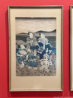 Full view of the framed Japanese woodblock print hung on a red wall, showing the entire artwork and frame.