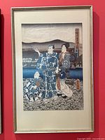 Framed Japanese woodblock print showing three figures in traditional dress with a scenic water and mountain background.