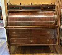 Front view of closed tambour roll-top with two lower drawers and brass-pierced gallery above