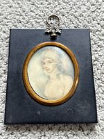 Frontal view of the miniature portrait within the oval wooden frame on a black backing, showing the overall artwork and framing.