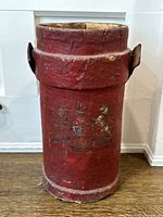 Front view of the red canvas cylinder showing painted crest and surface wear
