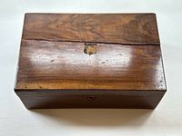 Top view of closed wooden box showing keyhole area, wood grain and crack across top.