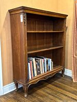 Three-quarter view of full bookcase showing shelves and carved apron