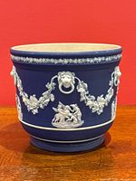 Front view showing cobalt blue body and white relief grapevine garlands and classical scene