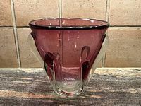 Front view of hand blown glass vase showing round flared purple bowl with clear glass accents.