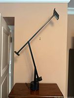 Full view of the lamp on a wooden surface showing base, articulated arms, and head.