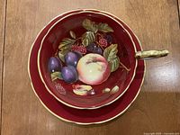 Top-down view of teacup nestled in saucer showing full fruit pattern interior and rim.