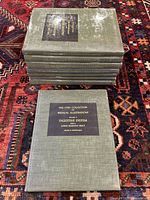 Stack of 8 CIBA medical illustration books with green cloth covers on a patterned rug.