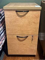 Front view showing two drawers, upper drawer without lock and lower drawer with lock and key hanging from keyhole.
