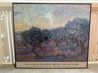 Framed Van Gogh exhibition poster showing olive tree painting with impressionist brush strokes in a black frame