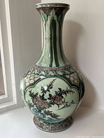 Full view of tall green porcelain vase showing bulbous body and narrow neck with leaf and geometric decoration.