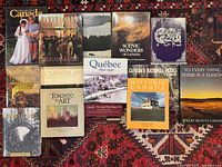 Photo showing 14 hardcover books about Canadian history, art, and landscape, arranged side by side on a decorative rug.